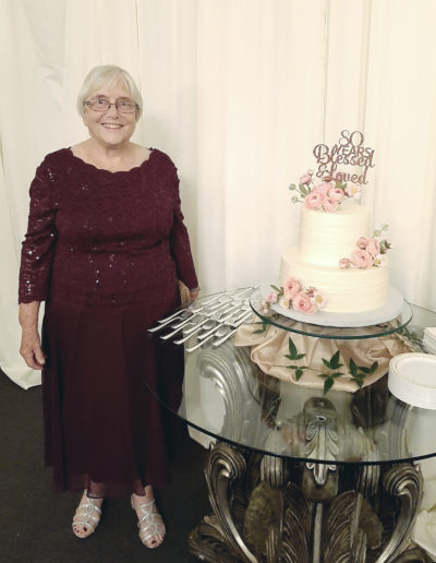 Lucinda standing beside two-tier decorated cake